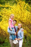 Junge liebevolle Paare von Eltern mit Kindertochter im Park auf Hintergrund des gelben blühenden Baums stockfotografie Junge liebevolle Paare von Eltern mit Kindertochter im Park auf Hintergrund des gelben blühenden Baums stockfotografie