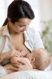 Junge Mutter, die ihr neugeborenes Kind hält Mutterkrankenpflegebaby Stillend Kind der hübschen Frau lizenzfreie stockfotos Junge Mutter, die ihr neugeborenes Kind hält Mutterkrankenpflegebaby Stillend Kind der hübschen Frau lizenzfreie stockfotos
