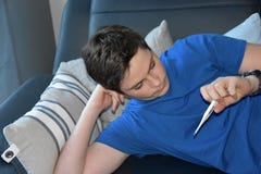 Junge nimmt seine Temperatur mit einem Fieberthermometer stockbilder Junge nimmt seine Temperatur mit einem Fieberthermometer stockbilder