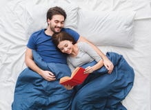 Junge Paare in der Draufsichtmorgenkonzept-Lesegeschichte des Betts stockfotografie Junge Paare in der Draufsichtmorgenkonzept-Lesegeschichte des Betts stockfotografie