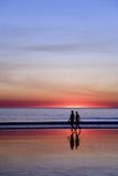 Junge Paare, die auf romantischen Strand am Sonnenuntergang gehen lizenzfreies stockfoto Junge Paare, die auf romantischen Strand am Sonnenuntergang gehen lizenzfreies stockfoto
