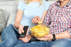 Junge Paare, die Chips beim Fernsehen essen stockfotos Junge Paare, die Chips beim Fernsehen essen stockfotos