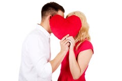 Junge Paare, die hinter dem Kissen flüstern Lizenzfreie Stockfotos Junge Paare, die hinter dem Kissen flüstern Lizenzfreie Stockfotos