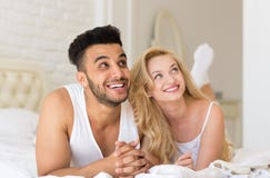 Junge Paare, die im Bett, im glückliches Lächeln-hispanischen Mann und in den Frauen-Liebhabern im Schlafzimmer liegen Lizenzfreies Stockbild Junge Paare, die im Bett, im glückliches Lächeln-hispanischen Mann und in den Frauen-Liebhabern im Schlafzimmer liegen Lizenzfreies Stockbild