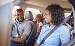 Junge schwarze Familie in einem Auto auf einem Autoreiselächeln stockfotografie Junge schwarze Familie in einem Auto auf einem Autoreiselächeln stockfotografie