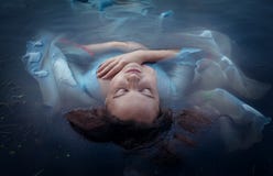 Junge schöne ertrunkene Frau im blauen Kleid, das im Wasser liegt lizenzfreies stockbild Junge schöne ertrunkene Frau im blauen Kleid, das im Wasser liegt lizenzfreies stockbild