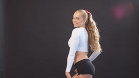 Junge sexy schöne Blondine in der stilvollen Eignungskleidung, die zur Kamera im Studio aufwirft stock video footage Junge sexy schöne Blondine in der stilvollen Eignungskleidung, die zur Kamera im Studio aufwirft stock video footage