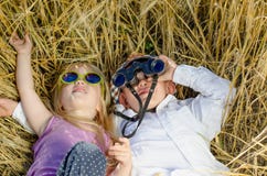 Junge und Mädchen, die im Gras mit Ferngläsern spielen Lizenzfreie Stockfotografie Junge und Mädchen, die im Gras mit Ferngläsern spielen Lizenzfreie Stockfotografie