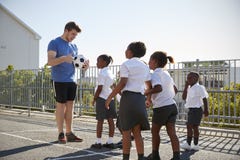 Jungen in einem Schulspielplatz mit dem Lehrer, der Ball hält lizenzfreie stockbilder Jungen in einem Schulspielplatz mit dem Lehrer, der Ball hält lizenzfreie stockbilder