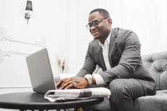 Junger Afroamerikanergesch?ftsmann in einer grauen Klage, die hinter einem Laptop arbeitet stockfoto Junger Afroamerikanergesch?ftsmann in einer grauen Klage, die hinter einem Laptop arbeitet stockfoto