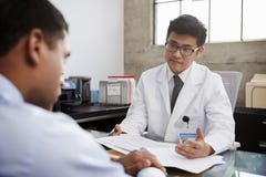 Junger asiatischer männlicher Doktor im Einvernehmen mit männlichem Patienten stockfotografie Junger asiatischer männlicher Doktor im Einvernehmen mit männlichem Patienten stockfotografie