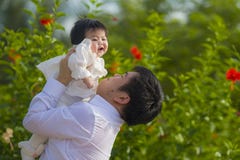 Junger glücklicher und stolzer Mann als Vater des süßen kleinen Babys, das ihre Tochter vor Blumengarten am Feiertagserholungsort lizenzfreie stockbilder Junger glücklicher und stolzer Mann als Vater des süßen kleinen Babys, das ihre Tochter vor Blumengarten am Feiertagserholungsort lizenzfreie stockbilder
