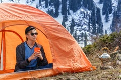 Junger Kerl mit einem Glas Tee oder Kaffee sitzt in einem touristischen Zelt an einem Halt in den Bergen vor dem hintergrund eine stockfotos Junger Kerl mit einem Glas Tee oder Kaffee sitzt in einem touristischen Zelt an einem Halt in den Bergen vor dem hintergrund eine stockfotos