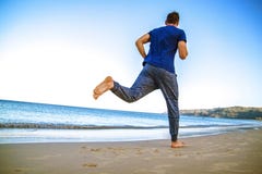 Junger Mann, der auf dem Strand in der Sportkleidung läuft lizenzfreies stockfoto Junger Mann, der auf dem Strand in der Sportkleidung läuft lizenzfreies stockfoto