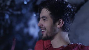 Junger Mann in der roten Kleidung lächelt und zieht langsam in Wald des verschneiten Winters um stock footage Junger Mann in der roten Kleidung lächelt und zieht langsam in Wald des verschneiten Winters um stock footage