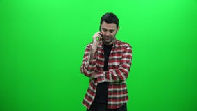 Junger Mann, der am Telefon gegen einen grünen Schirm spricht stock video Junger Mann, der am Telefon gegen einen grünen Schirm spricht stock video