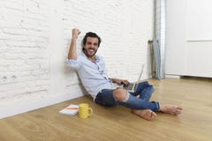 Junger Mann im modernen Blick der zufälligen Art des Hippies, der auf dem Wohnzimmerausgangsboden arbeitet an Laptop sitzt Stockfotografie Junger Mann im modernen Blick der zufälligen Art des Hippies, der auf dem Wohnzimmerausgangsboden arbeitet an Laptop sitzt Stockfotografie