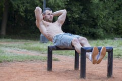 Junger muskulöser junger Mann, der SitzenUPS im Park tut stockfoto Junger muskulöser junger Mann, der SitzenUPS im Park tut stockfoto