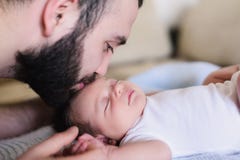 Junger Vater küsst sein neugeborenes Baby lizenzfreies stockfoto Junger Vater küsst sein neugeborenes Baby lizenzfreies stockfoto