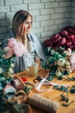 Junger weiblicher Florist, der am Telefon spricht und Anmerkungen am Blumenladen macht lizenzfreie stockfotografie Junger weiblicher Florist, der am Telefon spricht und Anmerkungen am Blumenladen macht lizenzfreie stockfotografie