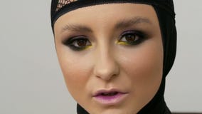 Junges Berufsmädchenmodell mit schönem Make-up und braunen den Augen, die in einer schwarzen Kappe auf ihrem Kopf vor aufwerfen stock video Junges Berufsmädchenmodell mit schönem Make-up und braunen den Augen, die in einer schwarzen Kappe auf ihrem Kopf vor aufwerfen stock video