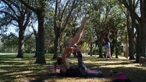 JUPITER, FLORYDA USA - CZERWIEC 17, 2017 Młode kobiety robi acro slackline na jawnym parku w Floryda & joga obraz royalty free JUPITER, FLORYDA USA - CZERWIEC 17, 2017 Młode kobiety robi acro slackline na jawnym parku w Floryda & joga obraz royalty free