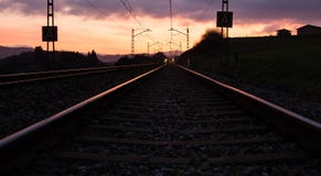 Järnvägsstation mot härlig himmel på solnedgången Industriellt landskap med järnväg, färgrik blå himmel med röda moln, sol arkivbild Järnvägsstation mot härlig himmel på solnedgången Industriellt landskap med järnväg, färgrik blå himmel med röda moln, sol arkivbild