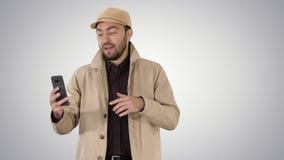 Молодой человек звоня видео- из его мобильного телефона пока идущ на предпосылке градиента стоковая фотография Молодой человек звоня видео- из его мобильного телефона пока идущ на предпосылке градиента стоковая фотография