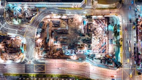 4K hyperlapse time-lapse of under construction site, crane, and car traffic transportation at night in city. Drone aerial top view