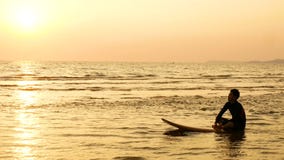 4K la siluetta dell'uomo del surfista si rilassa sedendosi sul surf sopra il mare al tramonto sulla spiaggia tropicale Sport e ri 4K la siluetta dell'uomo del surfista si rilassa sedendosi sul surf sopra il mare al tramonto sulla spiaggia tropicale Sport e ri