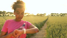 4K video clip of beautiful healthy mixed race African American girl teenager female young woman runner using smart watch at sunset