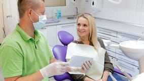 4k footage of male dentist talking to his patient and showing digital tablet