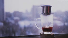 Kaffee tropft Tropfen einer Schale auf einem Hintergrund der Stadtlandschaft außerhalb des Fensters Gebräukaffee auf Vietnamesisc stock video Kaffee tropft Tropfen einer Schale auf einem Hintergrund der Stadtlandschaft außerhalb des Fensters Gebräukaffee auf Vietnamesisc stock video
