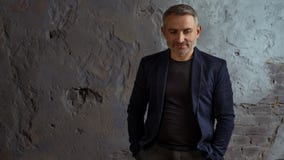Kall affärsman med grått hår- och skägganseende på grå bakgrund royaltyfria foton Kall affärsman med grått hår- och skägganseende på grå bakgrund royaltyfria foton