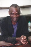 Kall le afrikansk man på hans arbetsplats arkivbild Kall le afrikansk man på hans arbetsplats arkivbild