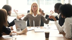 Kalme onderneemster die op vergadering met multiraciale collega's mediteren, geen spanning Kalme onderneemster die op vergadering met multiraciale collega's mediteren, geen spanning