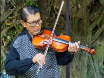 Kanchanaburi Thailand - December 25,2516: Asiatisk musikervioli royaltyfria bilder Kanchanaburi Thailand - December 25,2516: Asiatisk musikervioli royaltyfria bilder