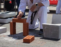 Karate ο φορέας σε ένα αθλητικό θέαμα σπάζει ένα τούβλο με το χέρι του στοκ εικόνες Karate ο φορέας σε ένα αθλητικό θέαμα σπάζει ένα τούβλο με το χέρι του στοκ εικόνες