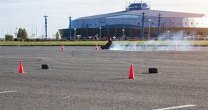 Karting konkurrenser, den karting chauffören kör en kart mot bakgrunden av en modern byggnad, mycket rök, vinnaren, affärsföretag royaltyfri bild Karting konkurrenser, den karting chauffören kör en kart mot bakgrunden av en modern byggnad, mycket rök, vinnaren, affärsföretag royaltyfri bild
