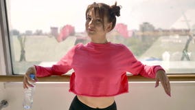 Kaukaska brunetka w różowej sportswear wodzie pitnej od butelki w białym pokoju zdjęcie wideo Kaukaska brunetka w różowej sportswear wodzie pitnej od butelki w białym pokoju zdjęcie wideo