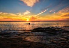 Kayaking Lake Superior in Summer, Michigan. A man kayaks in Lake Superior, in the Pictured Rocks National Lakeshore, Upper Peninsula of Michigan, as the sun is Kayaking Lake Superior in Summer, Michigan. A man kayaks in Lake Superior, in the Pictured Rocks National Lakeshore, Upper Peninsula of Michigan, as the sun is