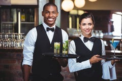 Kelner en serveerster die een dienend dienblad met glas van cocktail houden royalty-vrije stock fotografie Kelner en serveerster die een dienend dienblad met glas van cocktail houden royalty-vrije stock fotografie