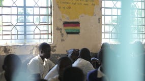 KENYA, KISUMU - MAY 23, 2017: Close-up fiew of three african boys in uniform sitting in classroom in school royalty free stock photography KENYA, KISUMU - MAY 23, 2017: Close-up fiew of three african boys in uniform sitting in classroom in school royalty free stock photography