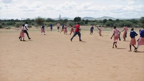 KENYA, KISUMU - MAY 20, 2017: Happy African children and Caucasian people playing football outside together. stock video footage KENYA, KISUMU - MAY 20, 2017: Happy African children and Caucasian people playing football outside together. stock video footage