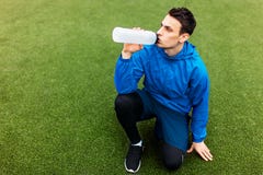 Kerel na oefening, drinkwater op het voetbalgebied Portret van mooie Kerel in sportkleding royalty-vrije stock afbeelding Kerel na oefening, drinkwater op het voetbalgebied Portret van mooie Kerel in sportkleding royalty-vrije stock afbeelding
