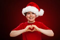 Kerstmistijd - jongen met Santa Claus Hat die hartteken tonen stock foto's Kerstmistijd - jongen met Santa Claus Hat die hartteken tonen stock foto's