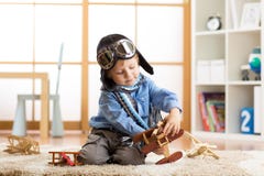 Kid boy weared aviator helmet plays with wooden toy planes in his children room Royalty Free Stock Photography Kid boy weared aviator helmet plays with wooden toy planes in his children room Royalty Free Stock Photography