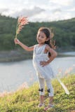 Kid fashion. Cute little asian girl wearing white clothes and flower grass in her hand. royalty free stock image Kid fashion. Cute little asian girl wearing white clothes and flower grass in her hand. royalty free stock image