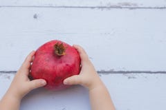 Kid hands holding Red Pomegranate on wooden background royalty free stock image Kid hands holding Red Pomegranate on wooden background royalty free stock image