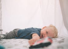 Kid is laying on the floor. Boy is playing in home with toy cars at home in the morning. Casual lifestyle in bedroom. stock photo Kid is laying on the floor. Boy is playing in home with toy cars at home in the morning. Casual lifestyle in bedroom. stock photo